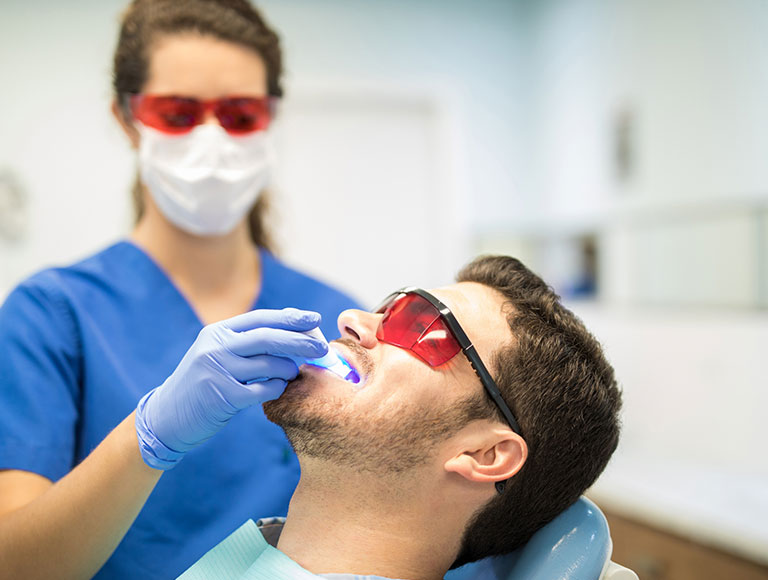Dental professional performing teeth whitening procedure in Huntington Beach