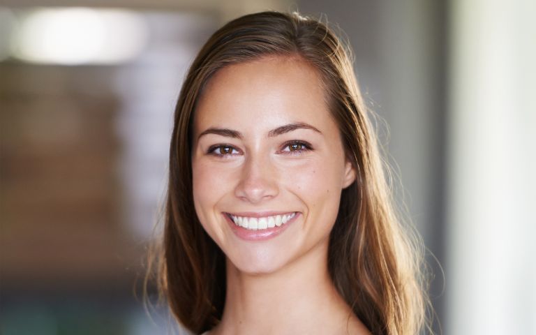 Woman smiling confidently outdoors after teeth whitening treatment in Huntington Beach